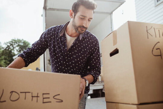 Man unloading cardboard boxes outside van