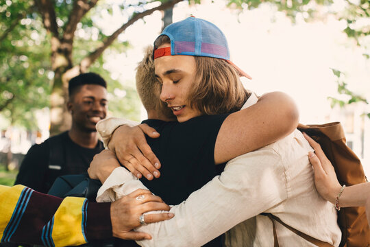 Hipster embracing male friend in park