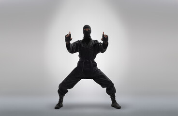 Fototapeta na wymiar japanese ninja in black uniform, on grey background