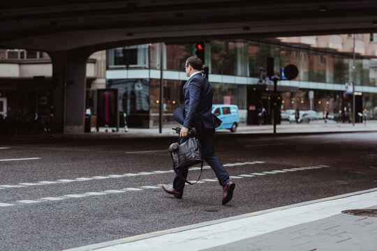 Businessman with bag crossing road in city