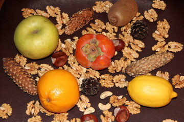 Bright orange persimmons and citrus fruits on a background of nuts