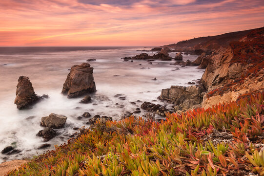 Scenic view of rocky coastline against sky during sunset