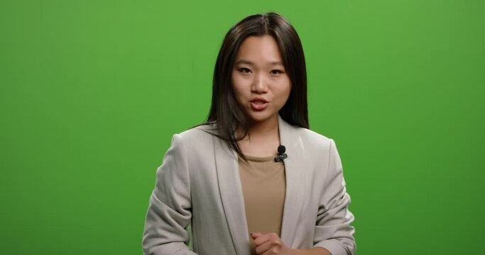 Television news reporter talking during an ad. Female anchor turning around in teaser of evening news program, shot on green chroma key background 4k footage