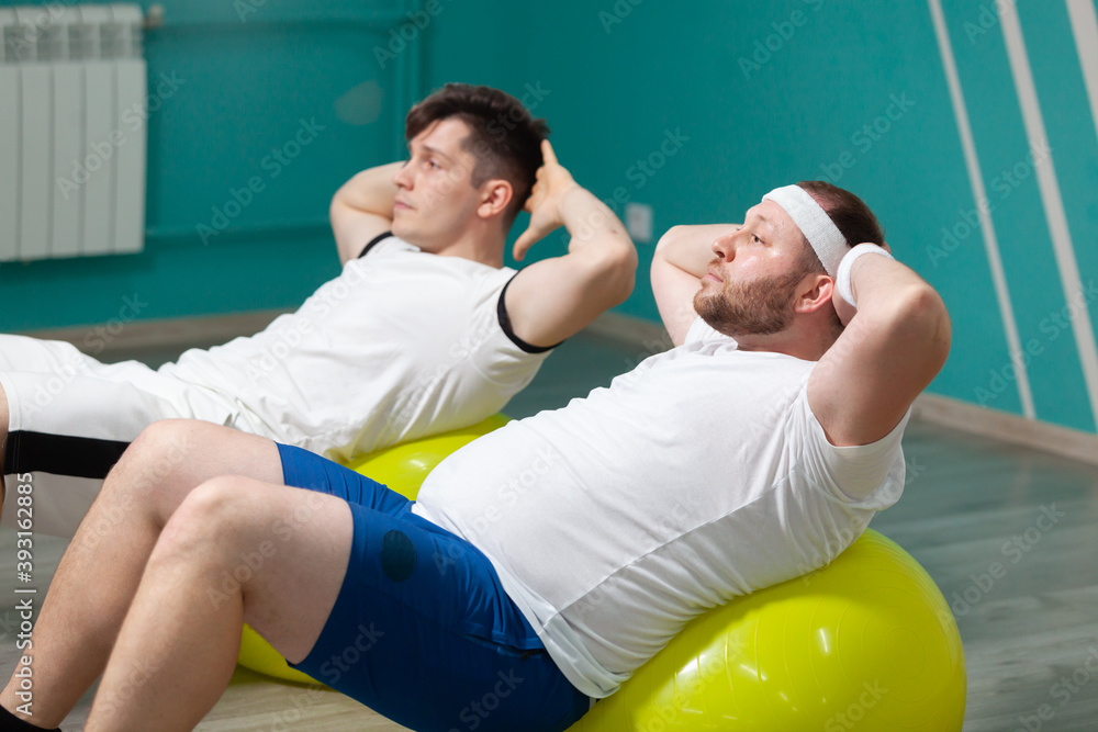 Wall mural tired fat man is lying on a fitness ball training during group fitness classes. overweight