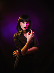 A woman in a black wig and a black, silk shirt, demonstrates open scissors in her hands.