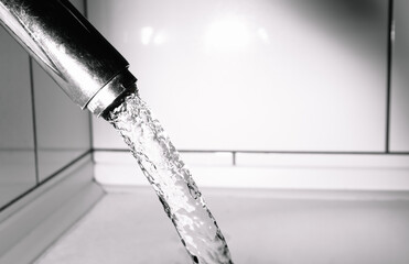 Pure and clear tap drinking water flows from the tap. Chrome plated fixtures are worn and have...