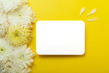 Blank isolated card on the bold yellow background with beautiful chrysanthemums on the background.Mockup for design.