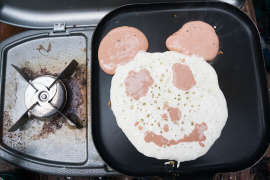 Overhead view of teddy bear shaped pancake cooking on grill pan