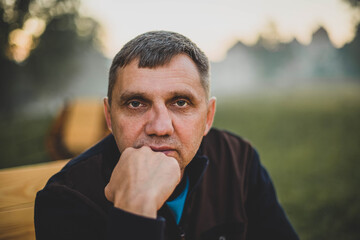 Fototapeta premium Outdoors portrait of a man in a street cafe on a background of fog. Senior Adult, Men. real people concept.