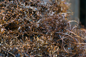 Steel scrap materials recycling. waste after machining metal parts on a cnc lathe. Closeup twisted spiral steel shavings. Small roughness sharpness