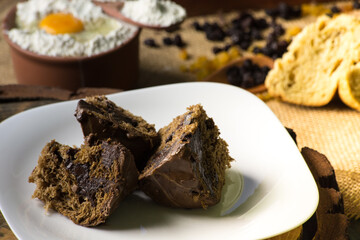 chocolate panettone on white plate. rustic table with ingredients