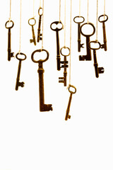 Antique skeleton keys hanging by string on white background