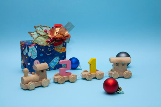 The children's train carries the number 21. The train on a blue background. Christmas decorations around the locomotive. Coming 2021