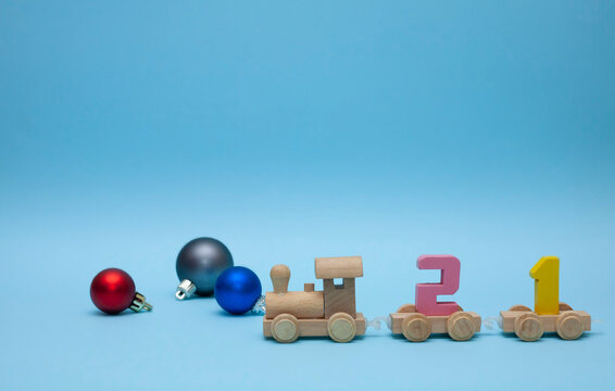 The children's train carries the number 21. The train on a blue background. Christmas decorations around the locomotive. Coming 2021