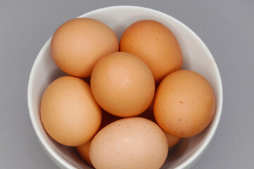 Brown chicken eggs in a cermic bowl on a gray background