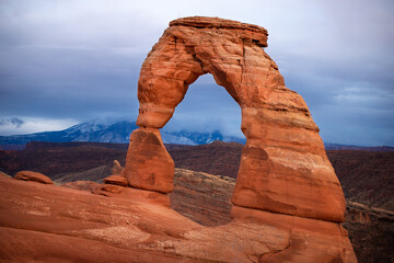 Delicate Arch in Arches National Park, Utah. A cloudy sunset, vibrant red rock. 