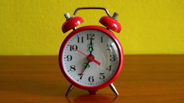 An alarm clock red rings in the morning on a bedside table - 7 o'clock and wake up to star the day - coffe and breakfast time
