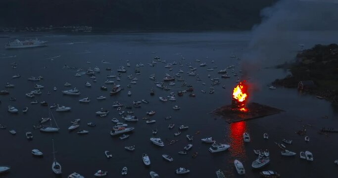 Amazing and beautiful, cinematic aerial footage that reveals the biggest bonfire event on Earth, the people and the small boats that are gathering around it near Alesund, Norway at dusk.