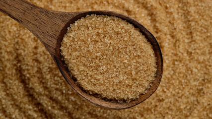 brown sugar in wooden spoon and sugar on background. Demerara golden brown sugar
