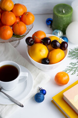 On a white background a cup with tea plates with tangerines, lemon and cherries, Christmas decor.