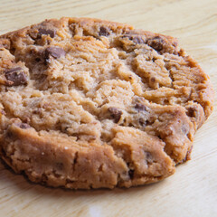 cookie with pieces of black and white chocolate on a wooden table.