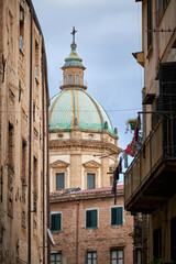 Fototapeta na wymiar View through a narrow street towards the dome of the church Santissimo Salvatore at Palermo