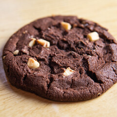 cookie with pieces of black and white chocolate on a wooden table.