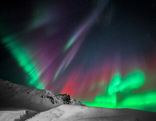 Vibrant Icelandic northern lights over mountain peaks in winter. 