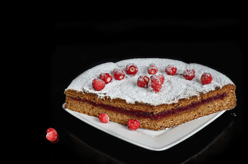 Homemade gingerbread cake with jam and fresh strawberries, on a black background. Selective focus