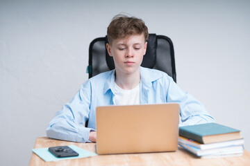 Coronavirus quarantine training. Cute caucasian boy is writing in a notebook during an online...