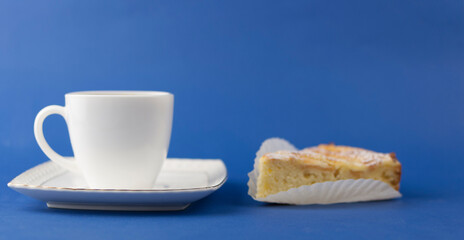 White ceramic cup of hot coffee and sweet pastries on blue background