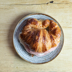 croissant with ham and cheese halved on a plate