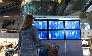 Woman looking at time table of flights at the airport.