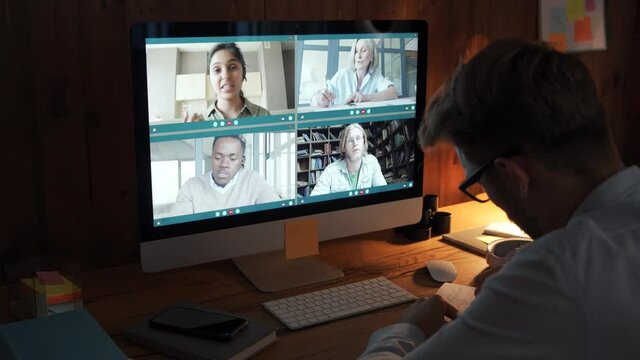 Business man having virtual team meeting on video conference call using computer. Social distance worker working from home office talking to diverse colleagues in remote videoconference online chat.