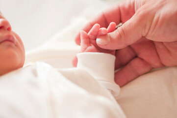 Mom holds a newborn baby by the handle