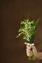 On a dark background, a white bouquet of lilies of the valley.
