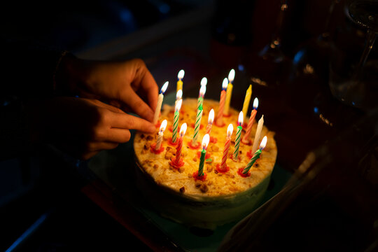 Hand placing candles on a birthday cake.