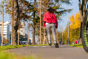 Active leisure. A sportive girl is rollerblading in an autumn park
