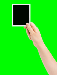 Woman hand drawing in the air with a black photo on a green isolated background. woman showing an instant photo