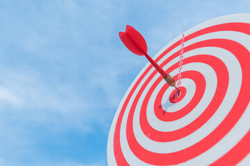 dart in target red circle center of the target dartboard on blue sky background