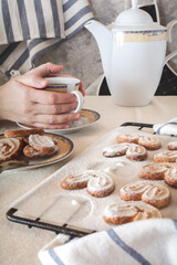 Anonymous lady is drinking tea with puff cookies. Selective focus.