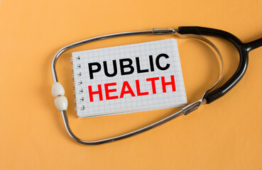 Notepad with text Public Health lies with a stethoscope on an orange background