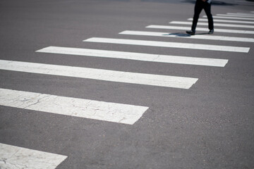 businessman crossing urban street with graphic lines of the crosswalk in the foreground