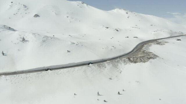 Trucks driving along a snow lined Colorado mountain road in the winter