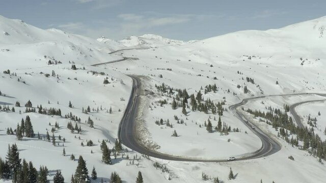 Curvy Colorado mountain road with snow capped mountains
