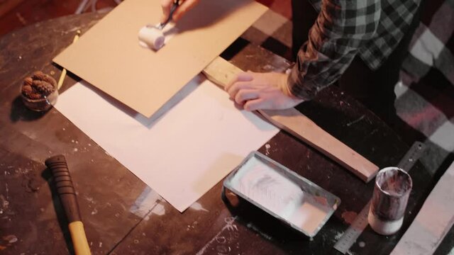 Man uses little Roller to priming the protest banner in domestic atmosphere. Preparing to a meeting.