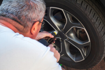 Fototapeta na wymiar Man changing his own car tire for winter season at home.