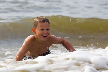 Young cheerful boy having fun at sea waves.