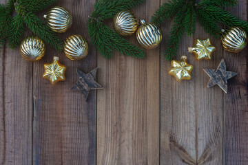Christmas tree twigs, golden Xmas balls and stars on wooden background. Vintage Christmas composition. Top view, flat lay, copy space.
