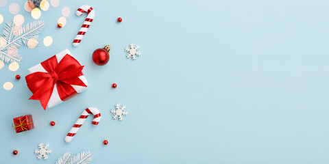 Christmas gift box with red bow and decorations on pastel blue background